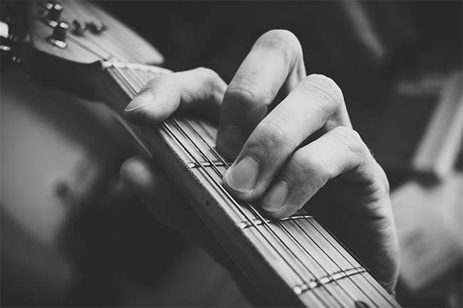 Man Playing Guitar Chord: Black and White